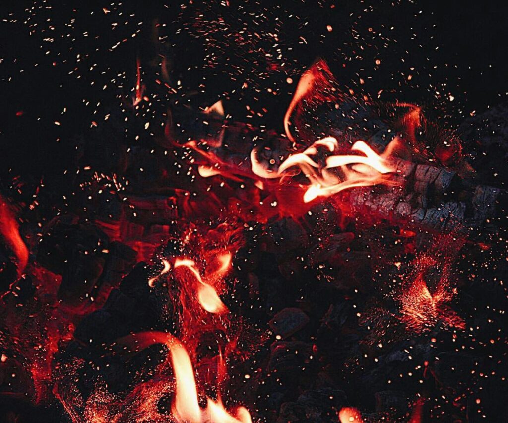 Dynamic close-up of red flames and sparks, showcasing intense heat and energy.